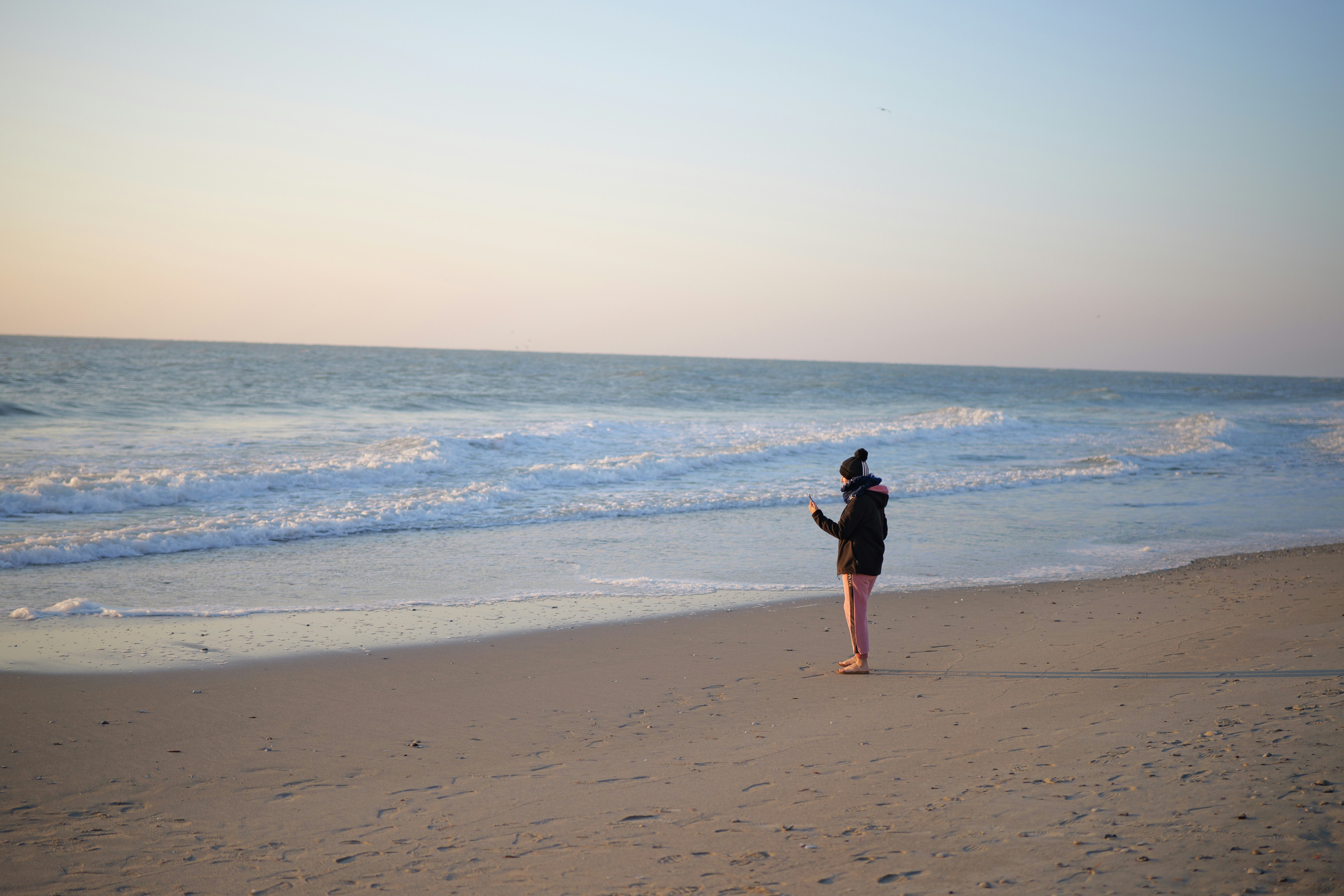 A person standing on a beach flying a kite