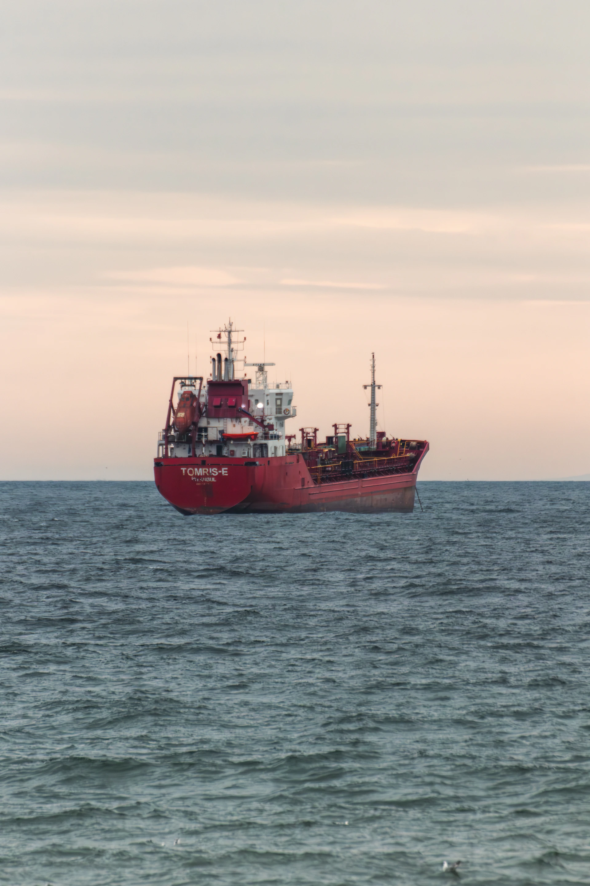 A large red boat floating on top of a large body of water