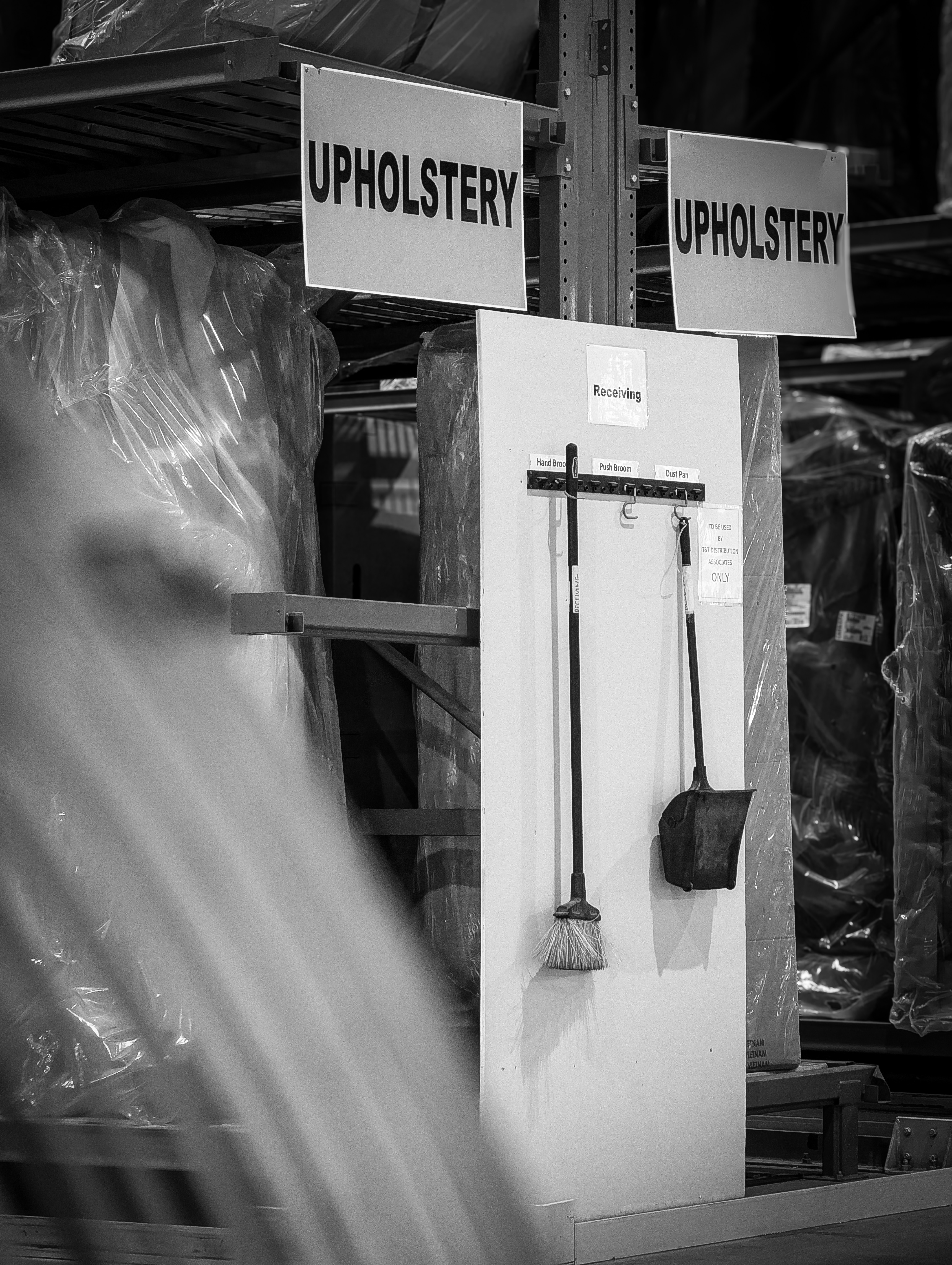 Broom and dustpan hanging on a warehouse shelving unit.