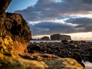 A large rock sitting on top of a beach next to the ocean