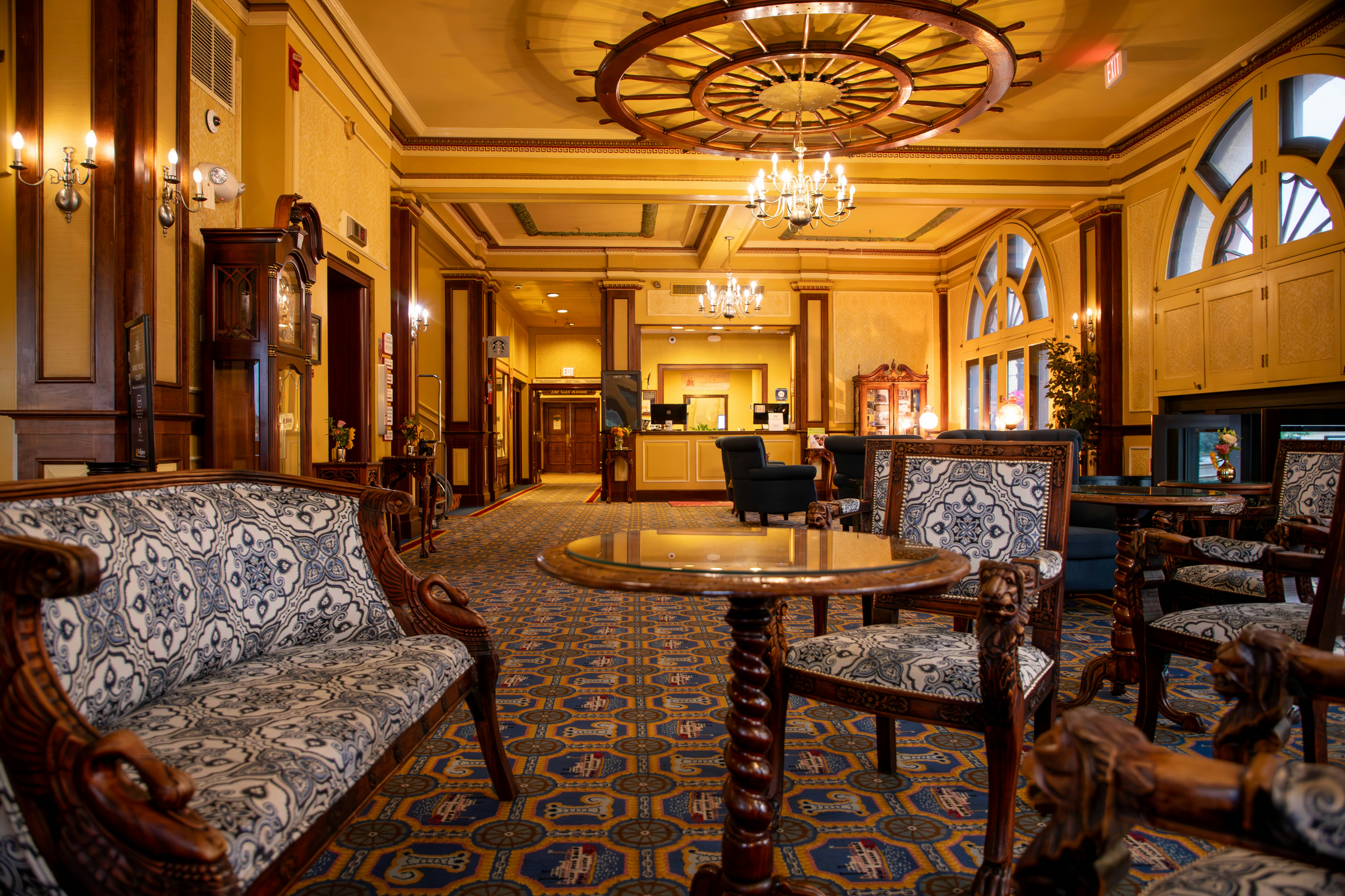 A hotel lobby with chairs, tables and chandeliers, 