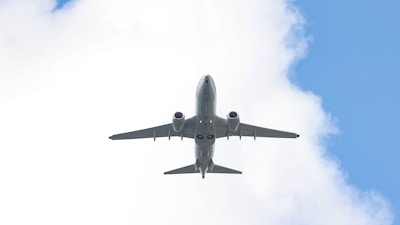 An airplane flying in the sky with a cloud in the background