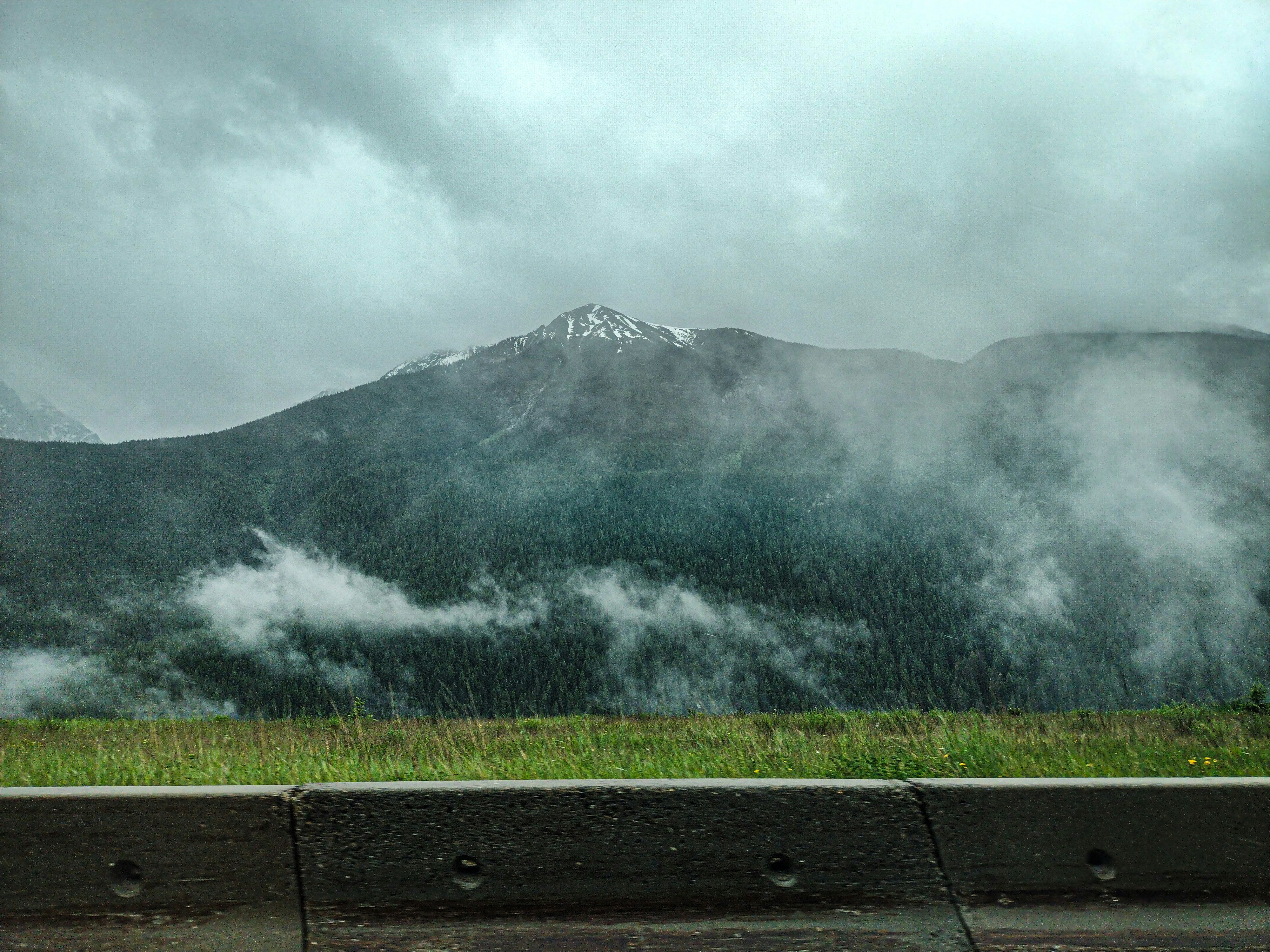 A bench sitting on the side of a road with a mountain in the background