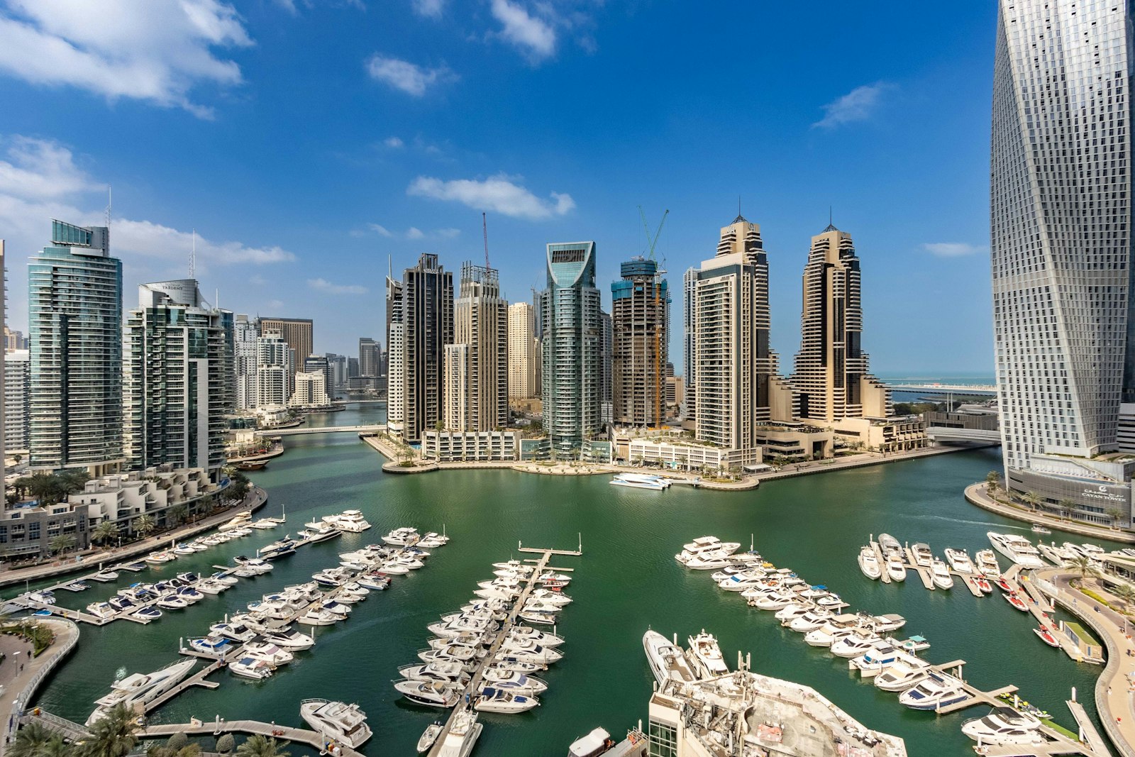 The towers and yacht-filled harbor of Dubai Marina under a blue sky