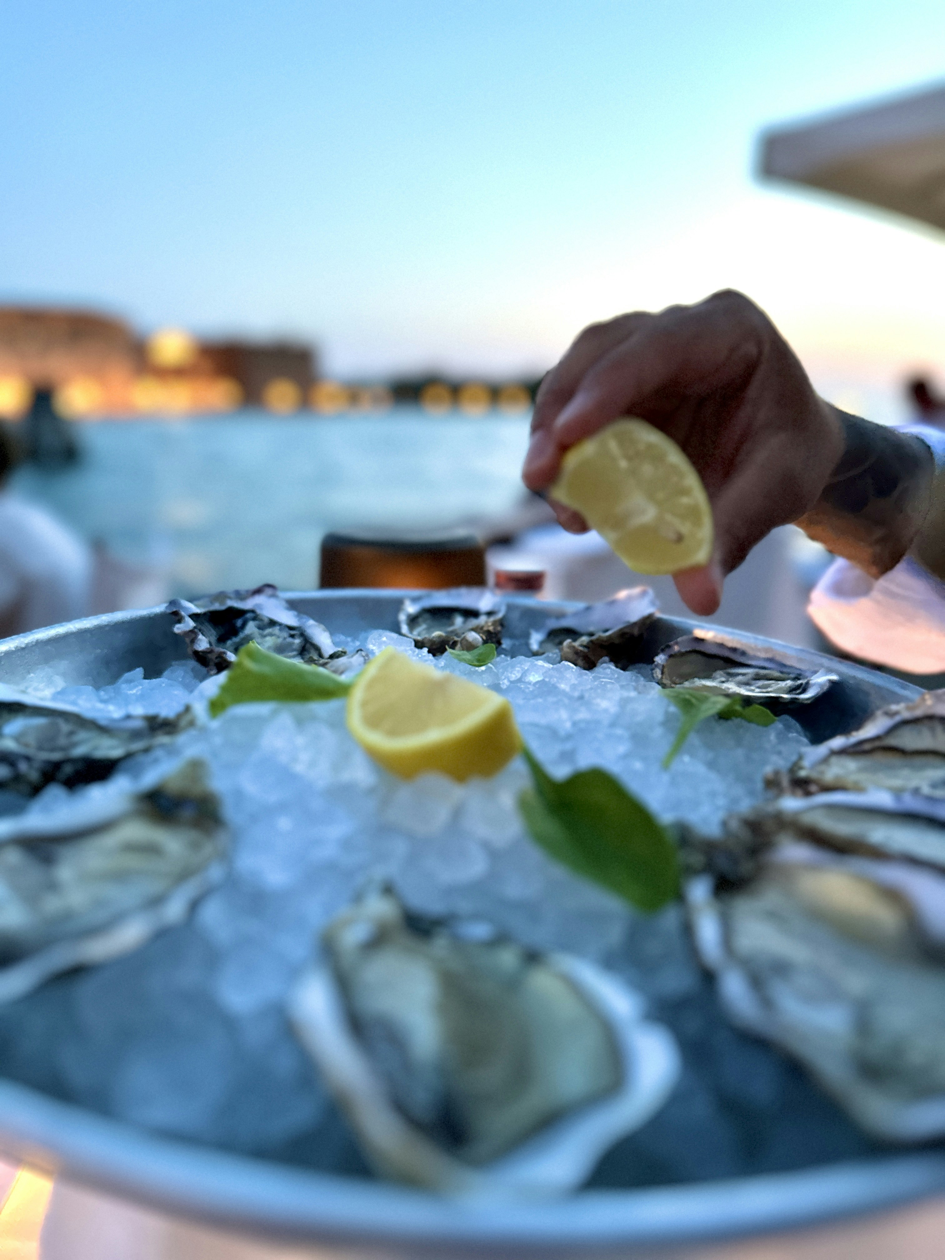 A plate of oysters with lemon wedges on a table