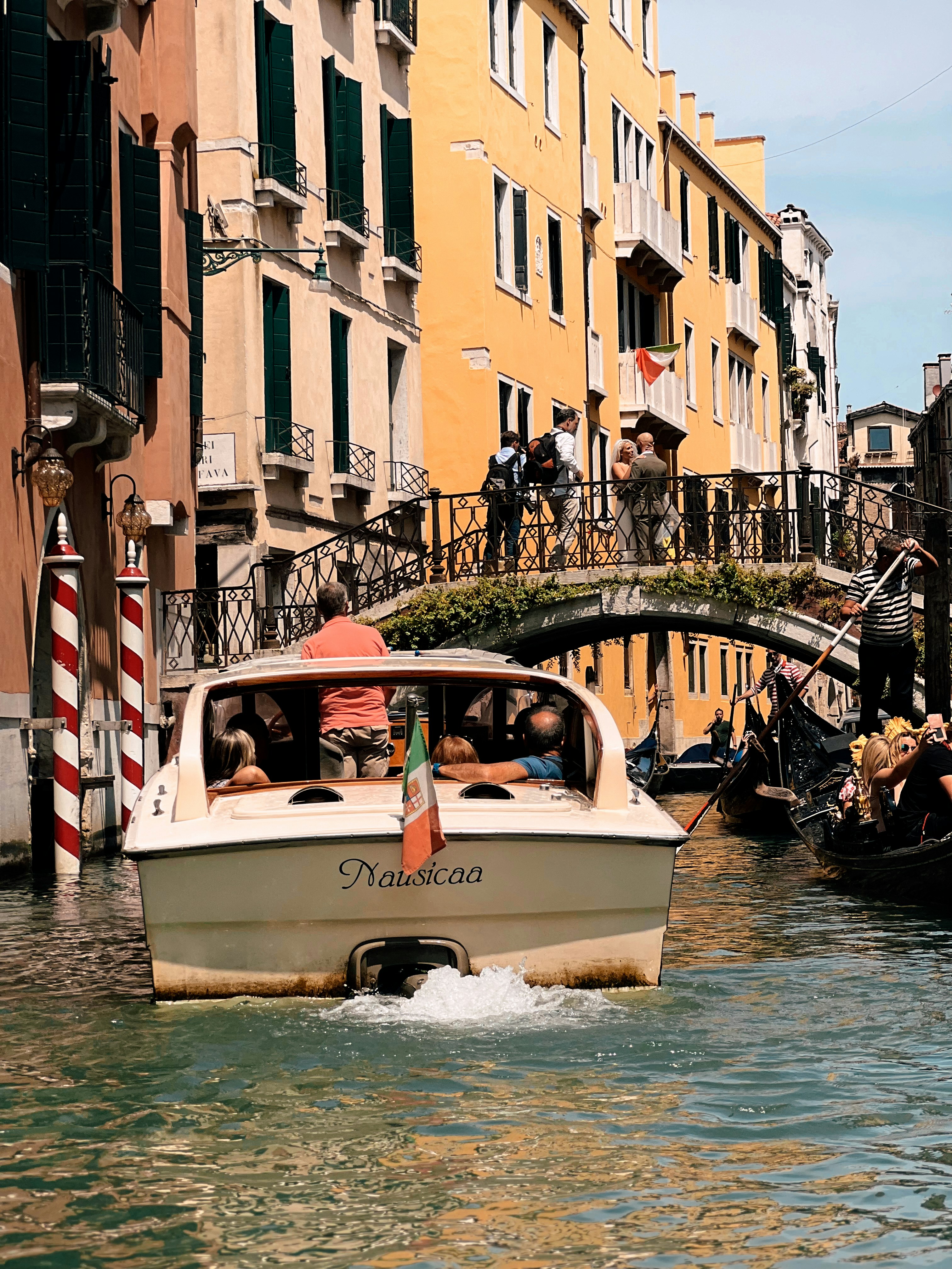A boat traveling down a canal next to tall buildings