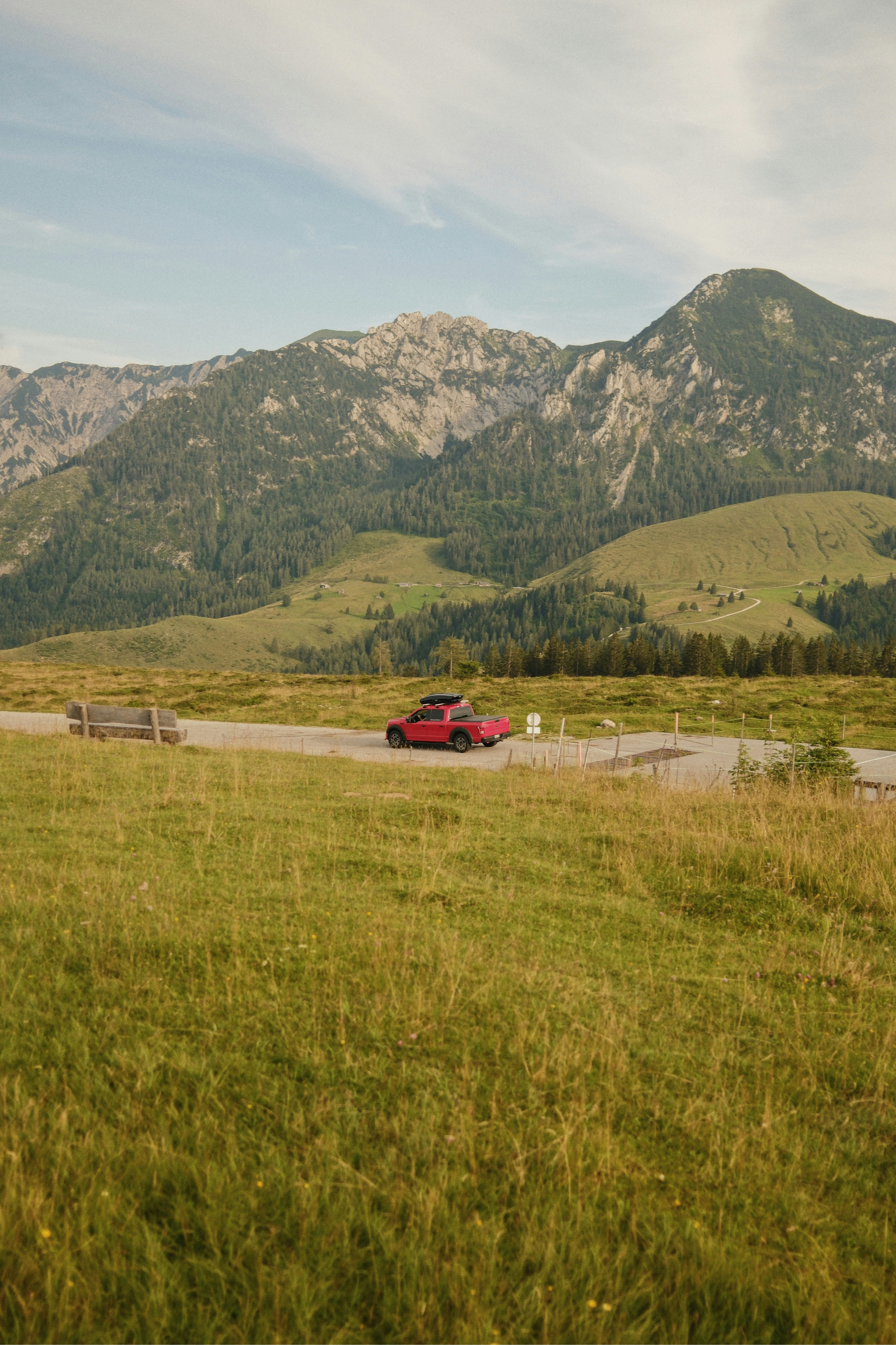 A red car driving down a country road