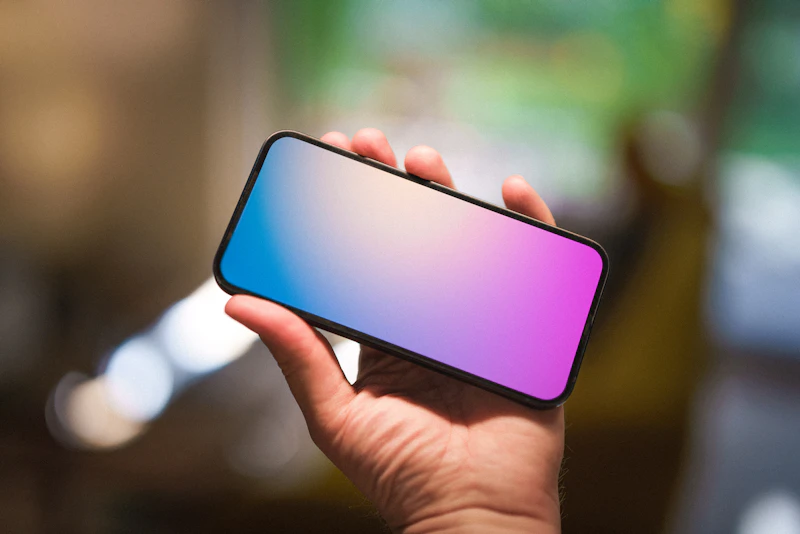 Hand holding a phone with a blue and pink screen