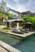 A pool with lounge chairs and umbrellas next to a house