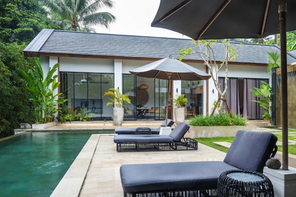 A pool with lounge chairs and an umbrella next to it