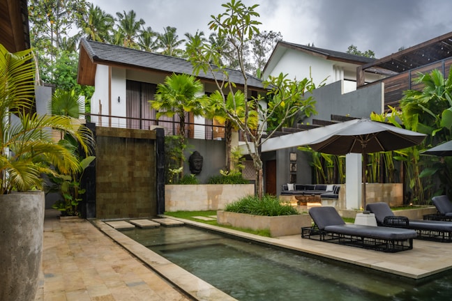 A pool in front of a house surrounded by greenery