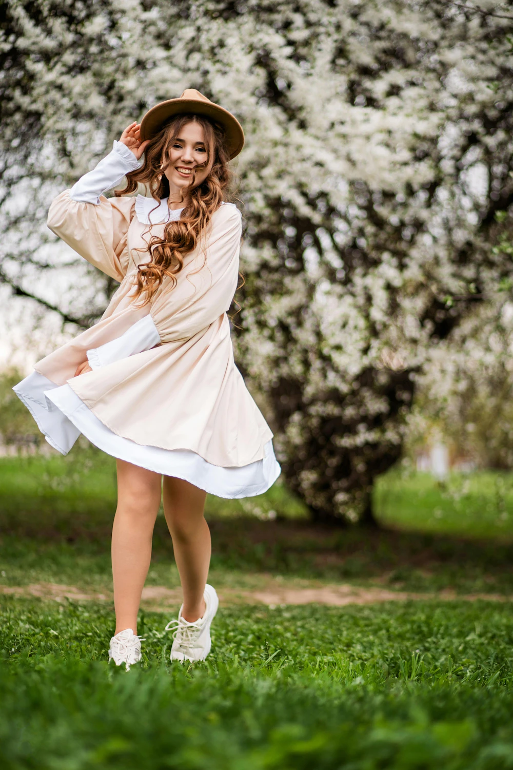 Woman in a dress and hat standing in tall grass