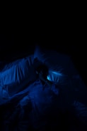 A person laying in a bed in a dark room