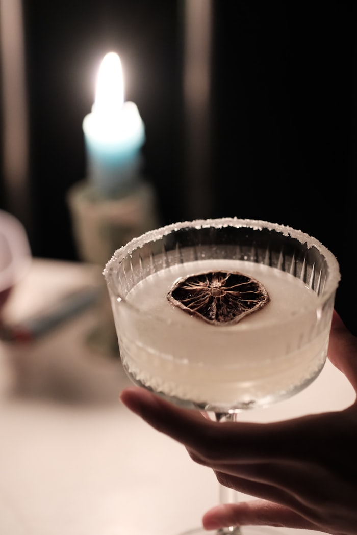Salt-rimmed coupe held up in the candlelight