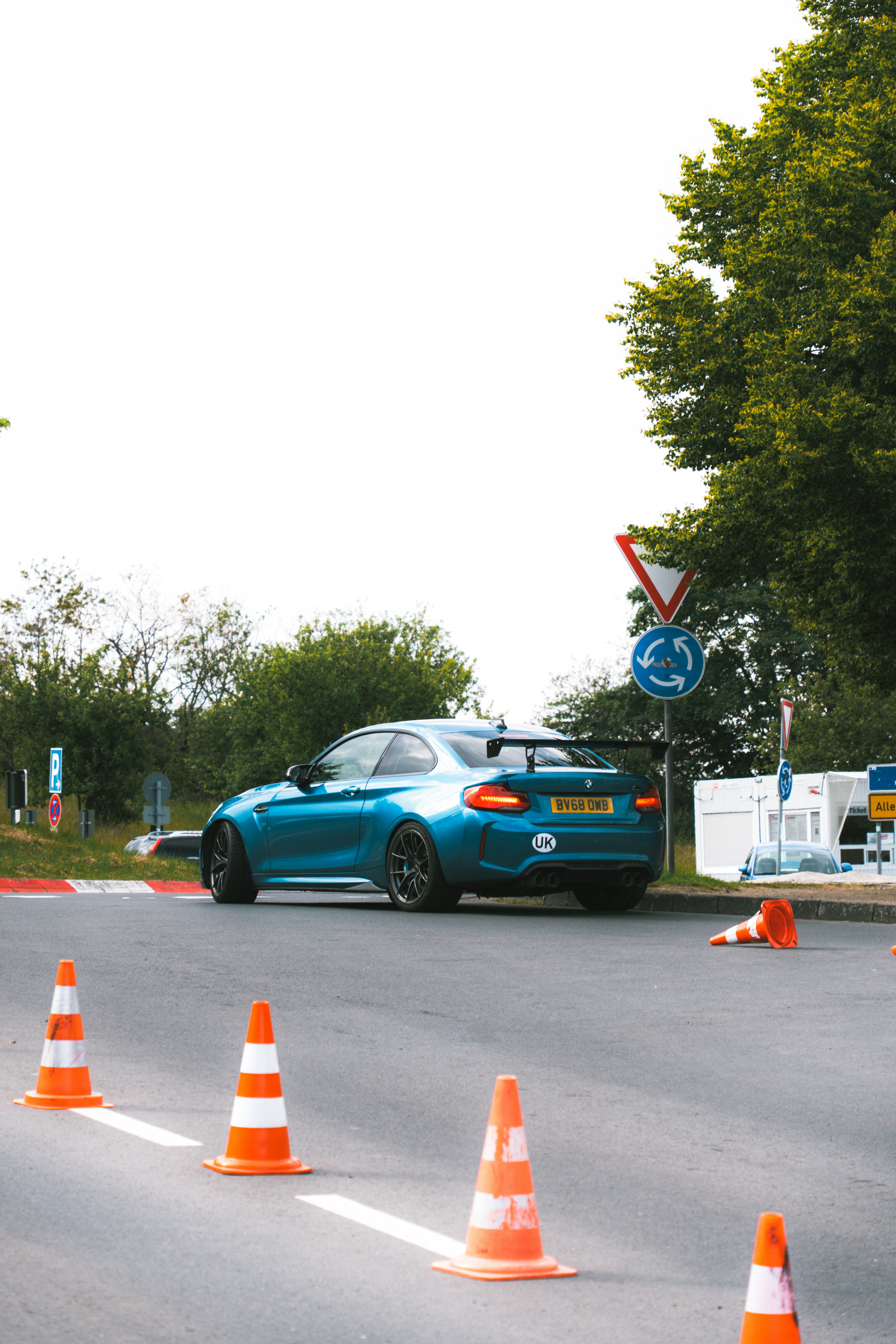 A blue car driving down a street next to orange cones