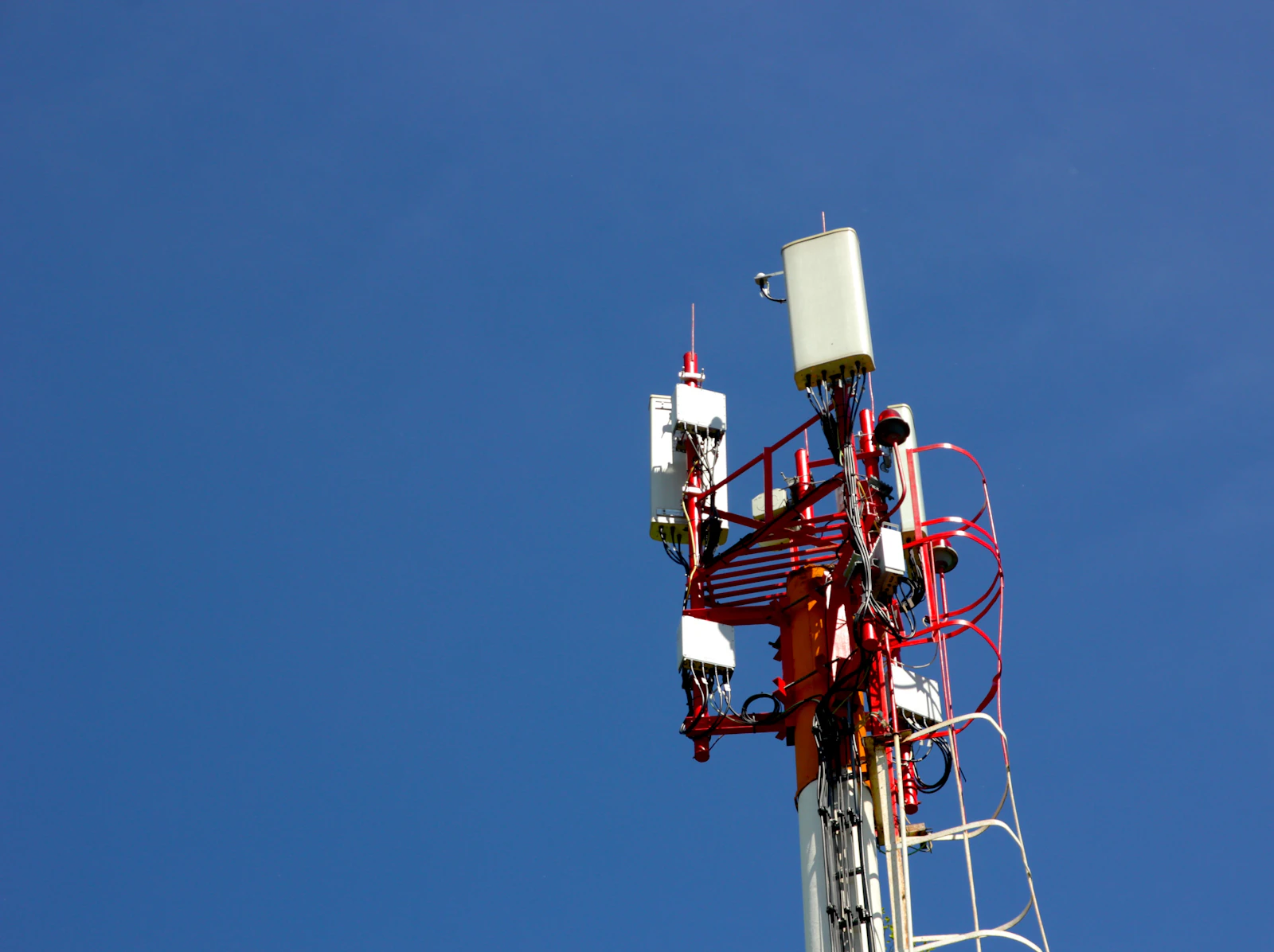 Cell tower against the sky representing antenna, line, and grounding installation work.
