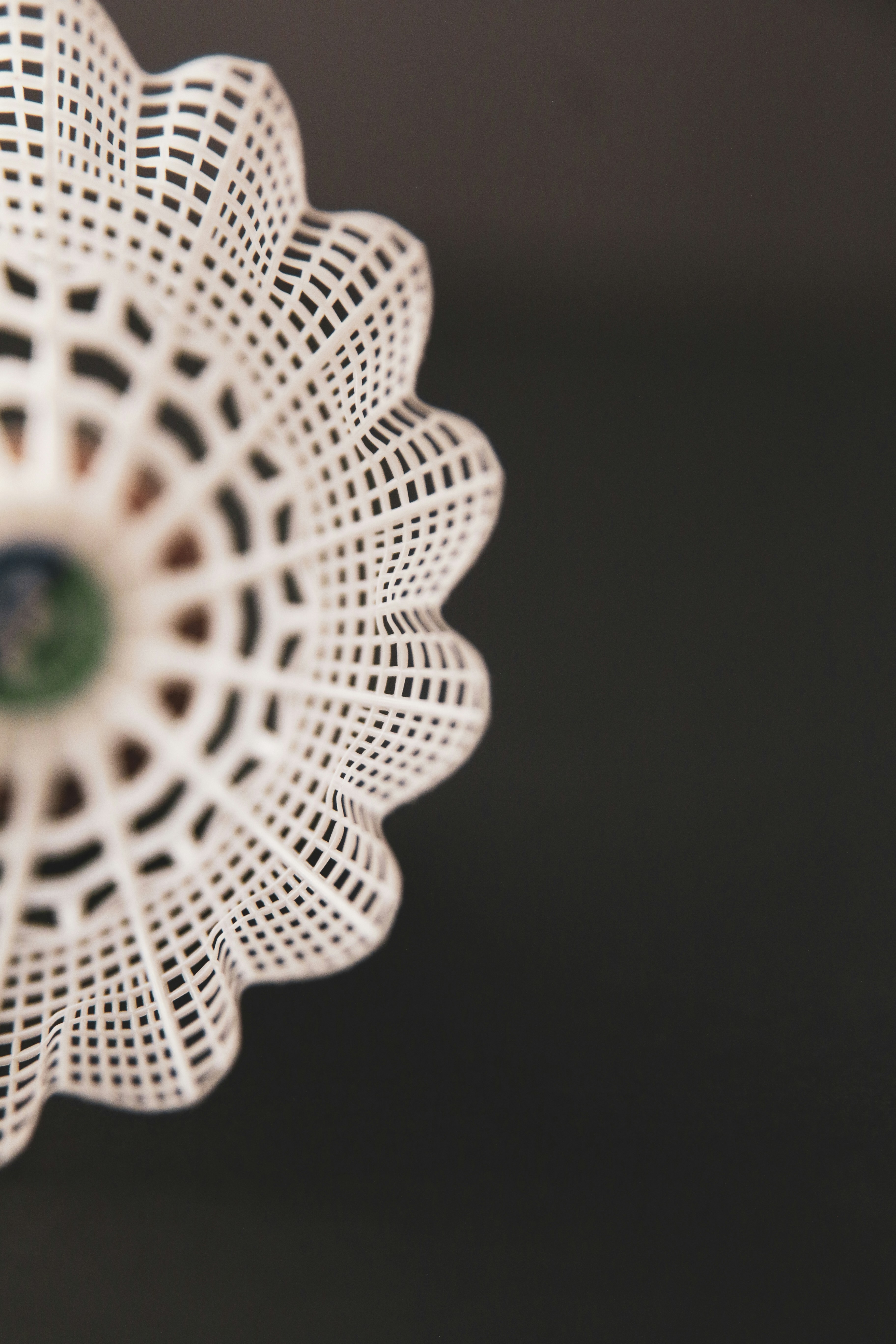 A white doily with a green center on a black surface