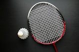 A tennis racket and a ball on a black surface