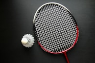 A tennis racket and a ball on a black surface