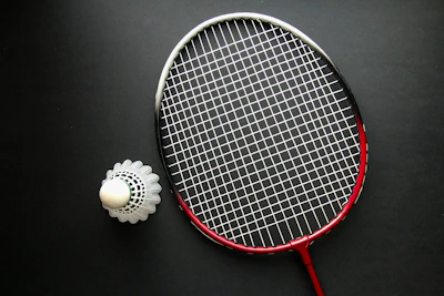 A tennis racket and a ball on a black surface