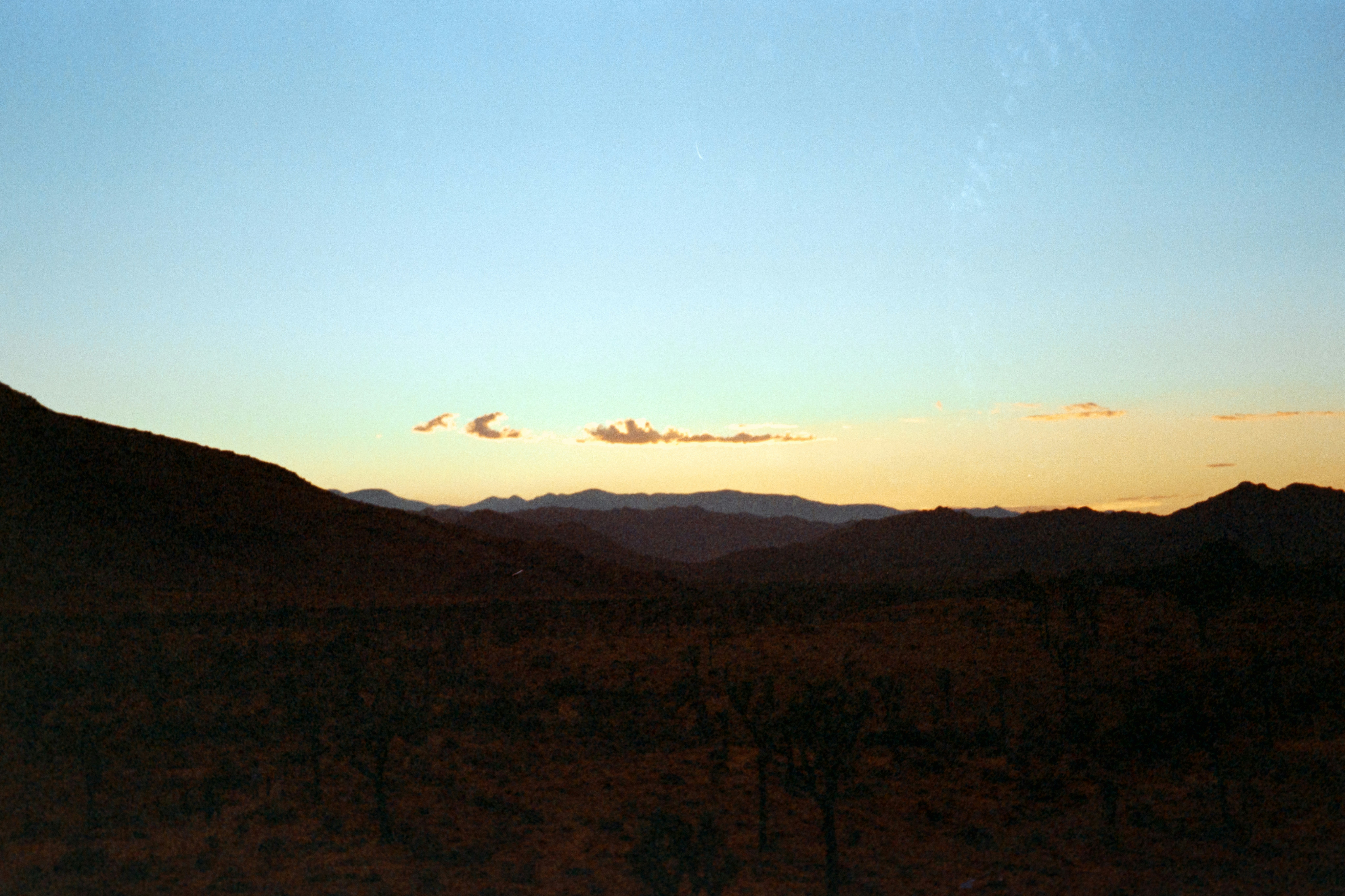 The sun is setting over the mountains in the distance