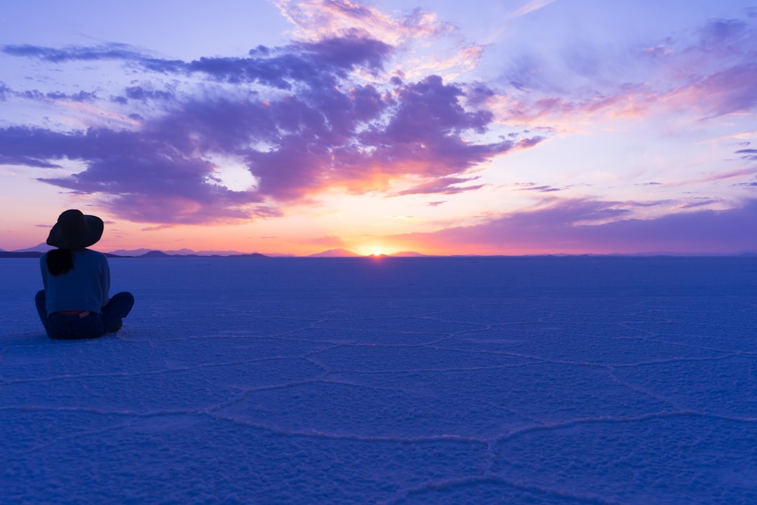A person sitting in the snow at sunset,