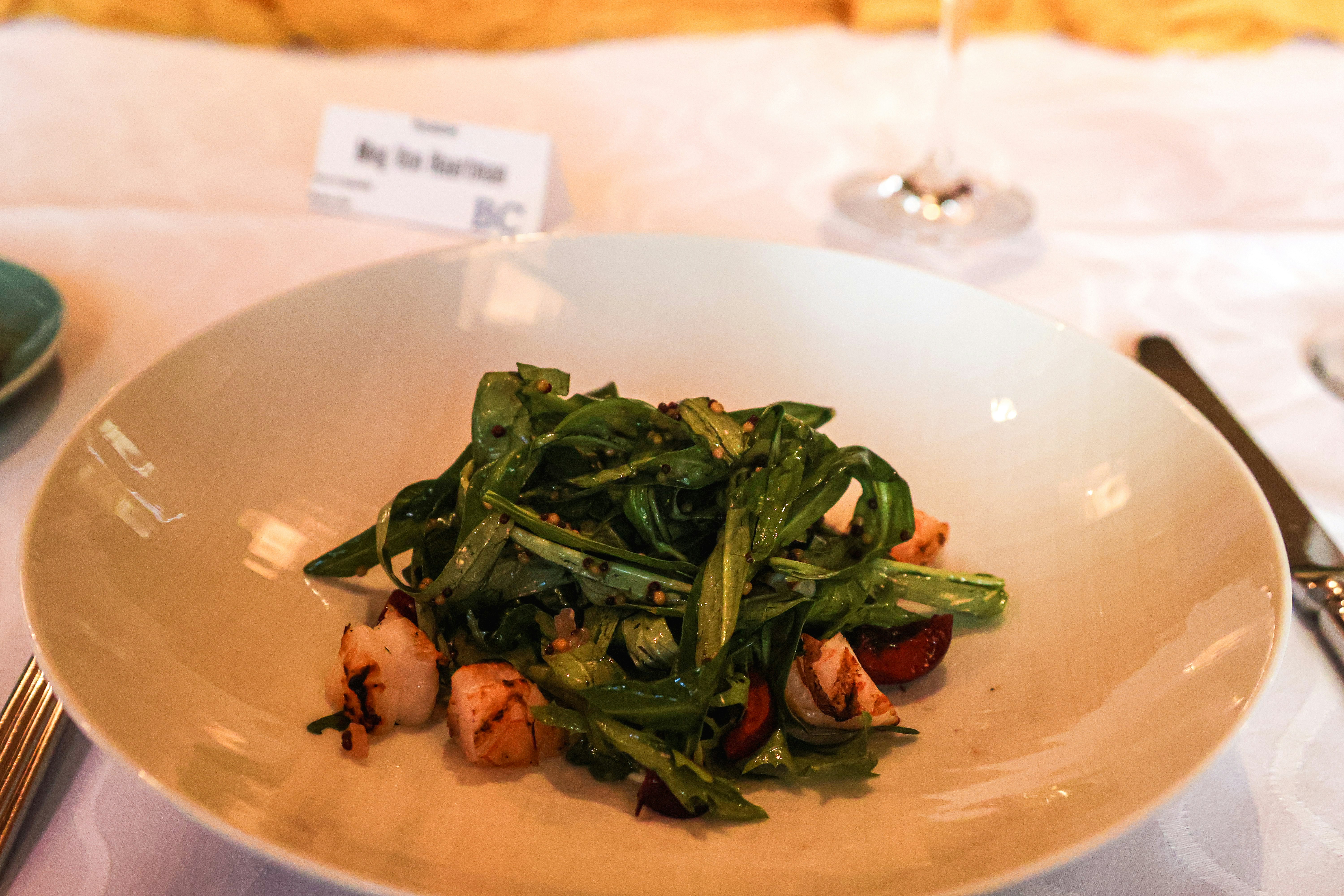 Greens on a white plate at a set table
