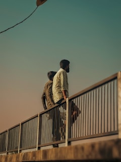 A couple of men walking across a bridge