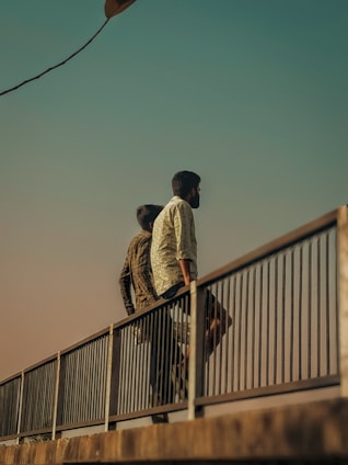 A couple of men walking across a bridge