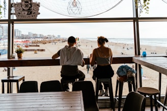 A couple of people sitting at a table in front of a window