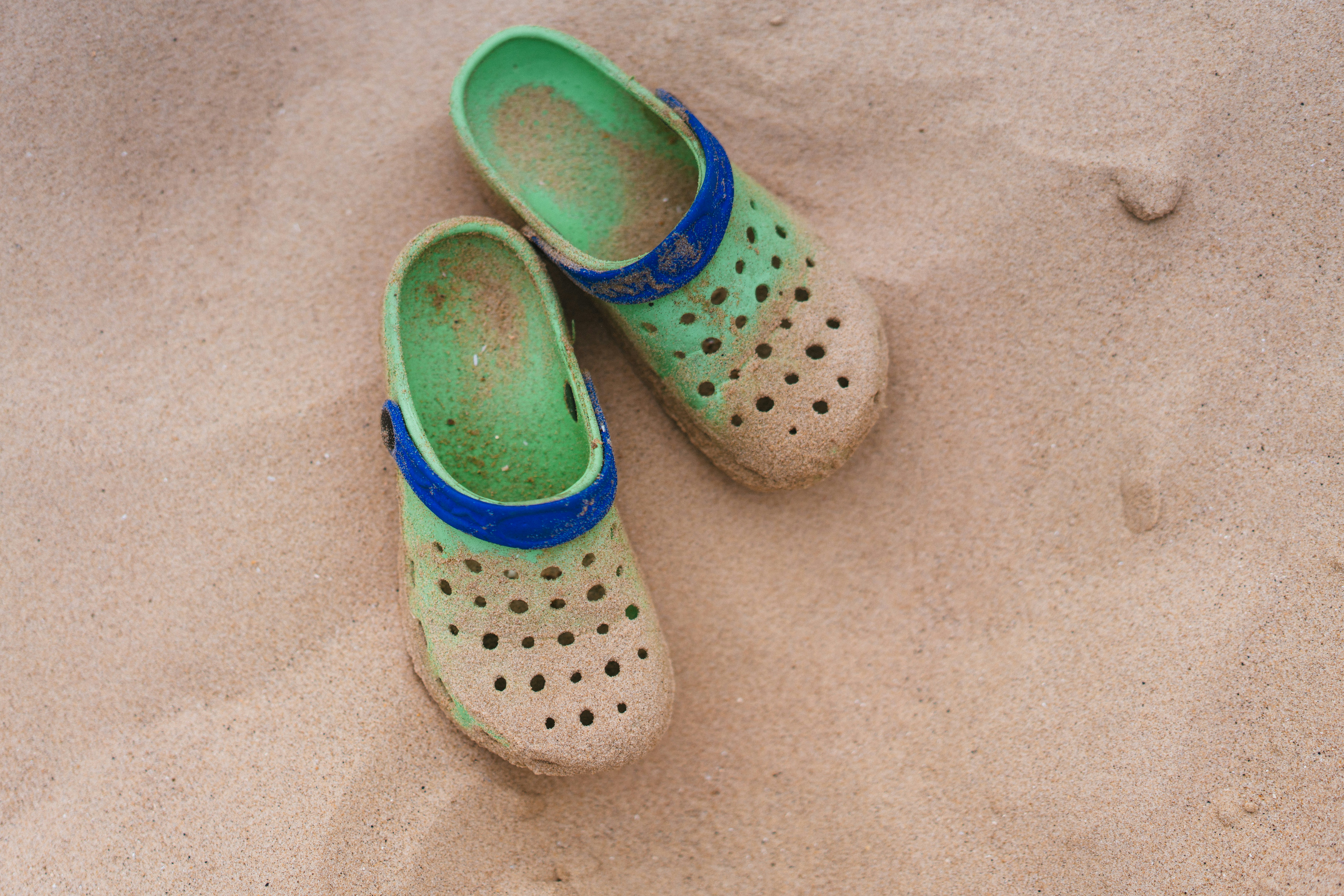 A pair of green shoes sitting on top of a sandy beach
