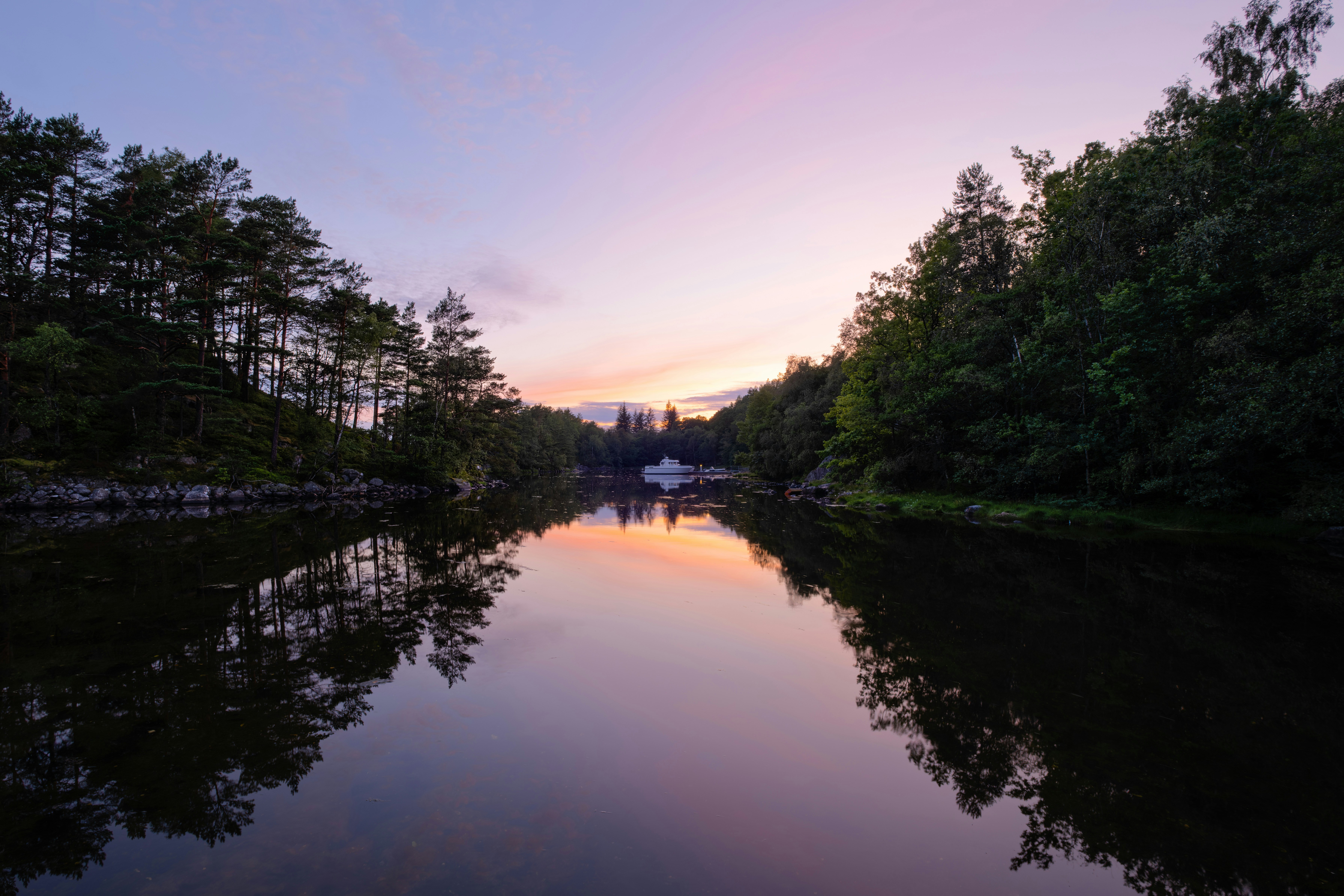 A body of water surrounded by trees and a bridge