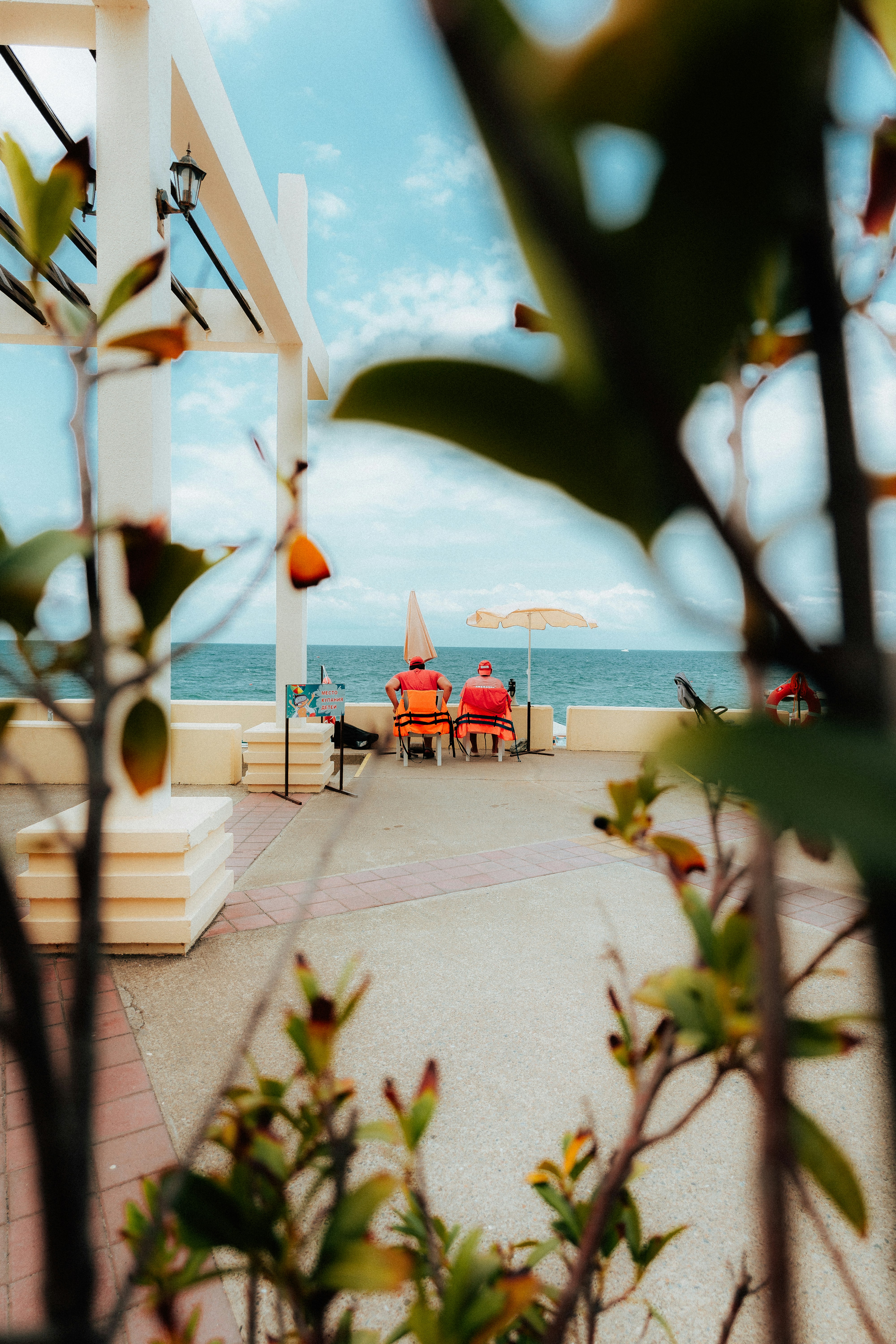 A couple of people sitting on a bench under an umbrella