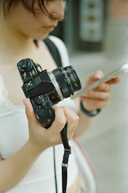 A woman holding a camera and a cell phone