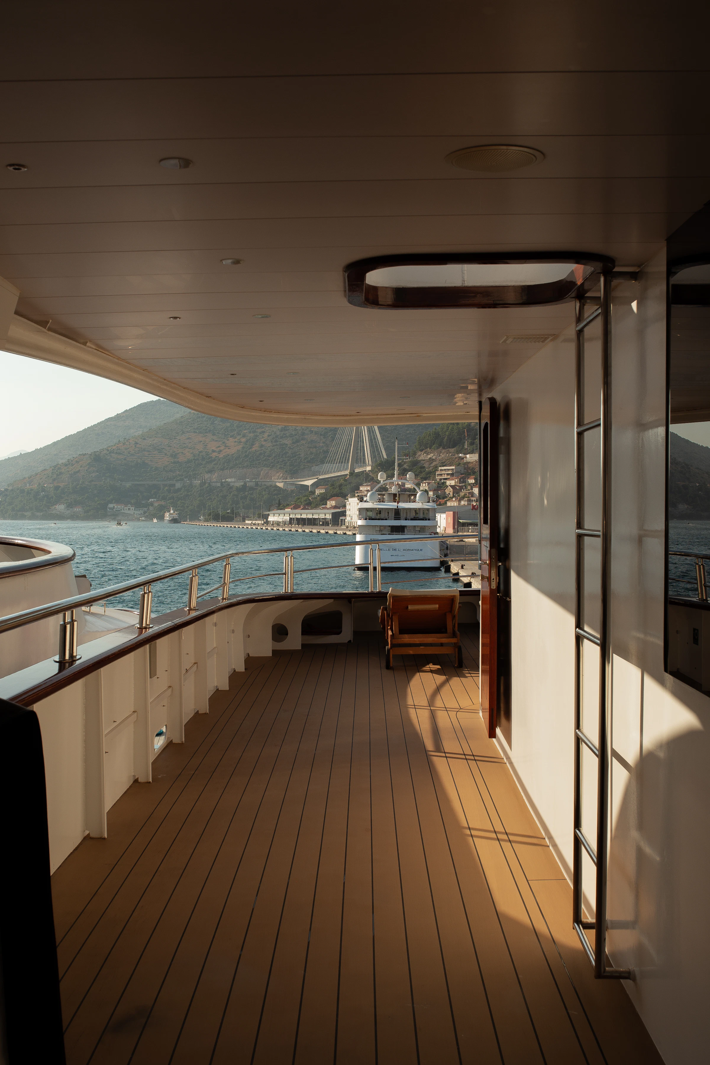 Golden-hour view down the teak deck of a superyacht