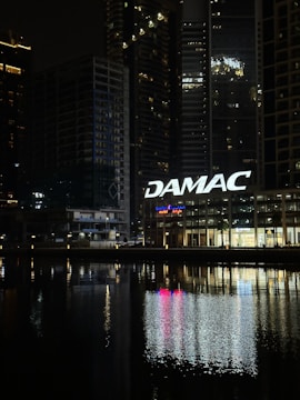 A view of a city at night with a sign that says damac
