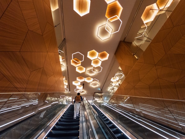 An escalator in a building with lights hanging from the ceiling