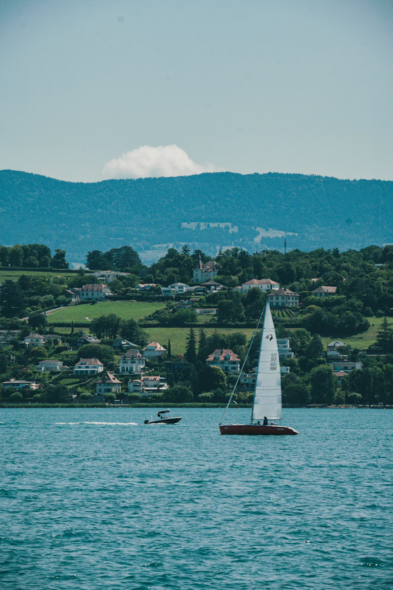 Sailboat and motor boat on Lake Geneva with the Alps behind