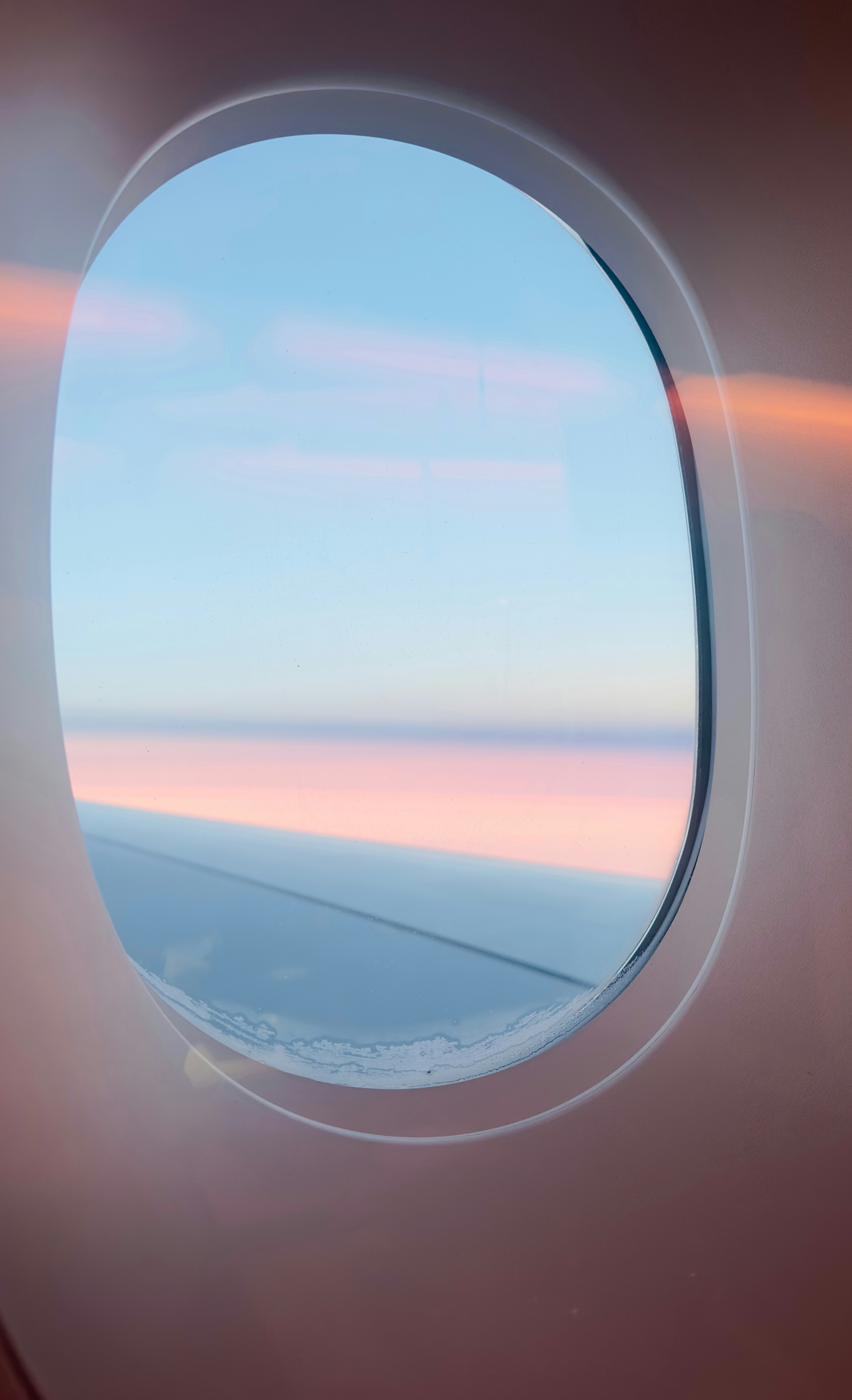 An airplane window with a view of the sky