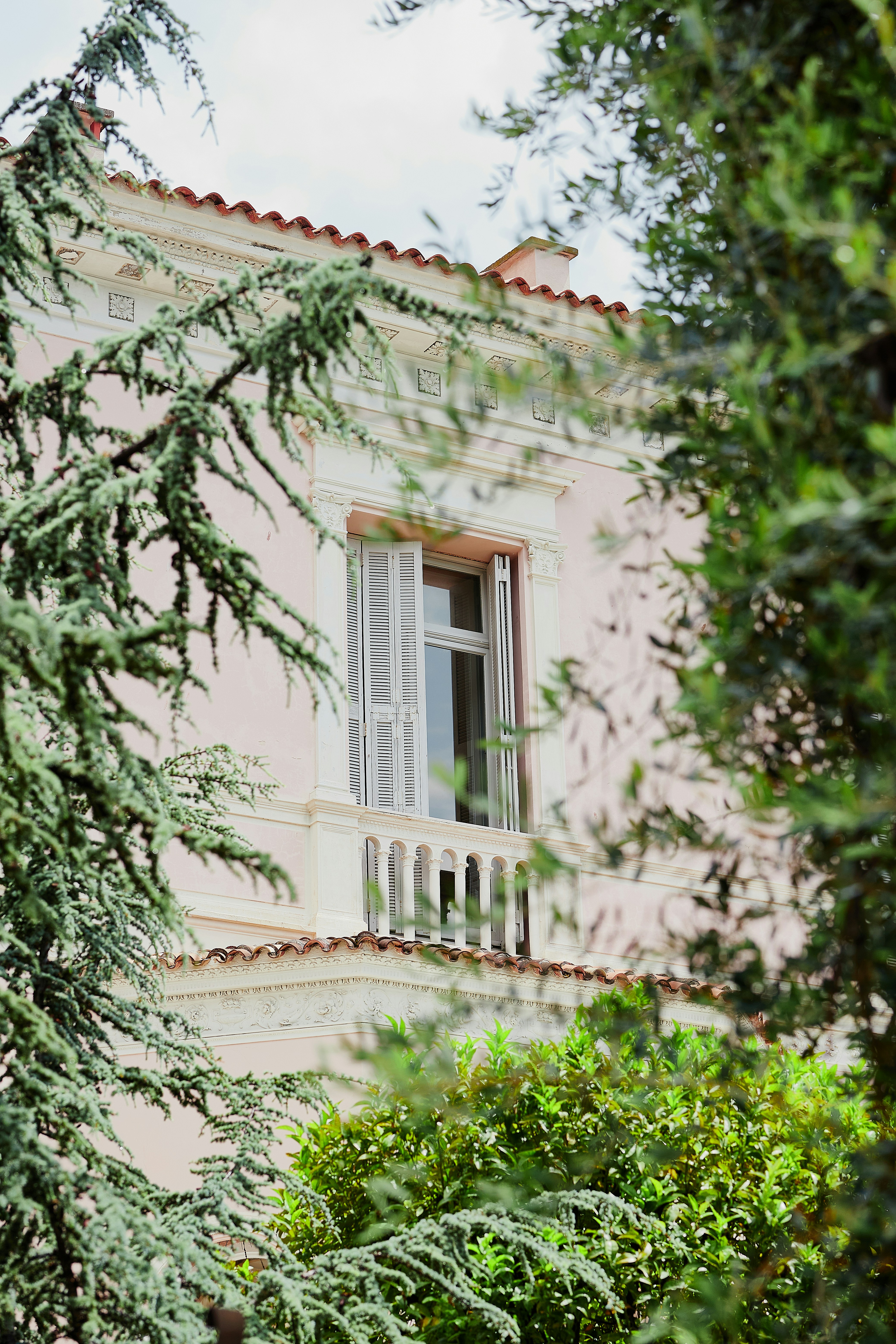 A pink building with white windows and a balcony