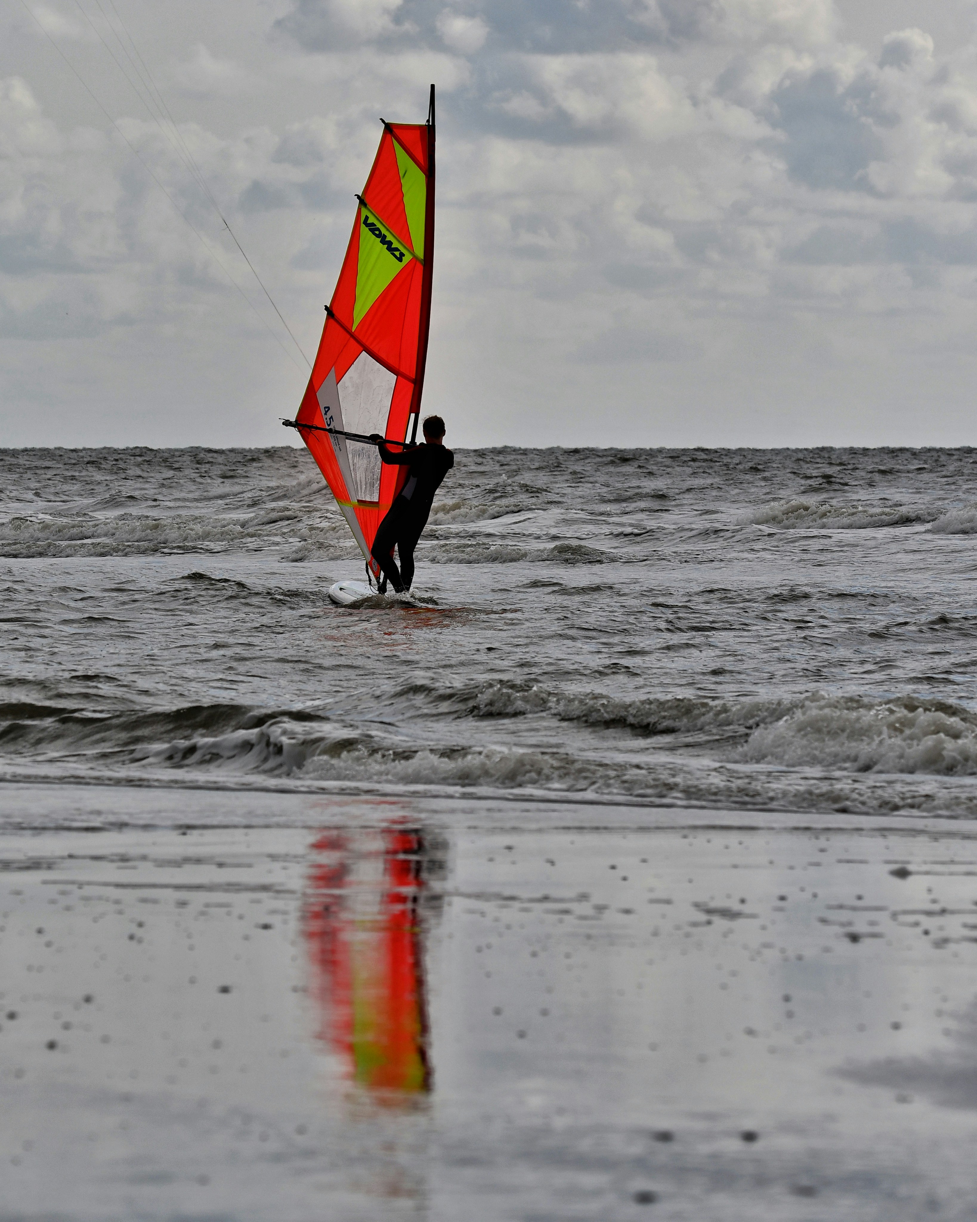 A person windsurfing in the ocean on a cloudy day