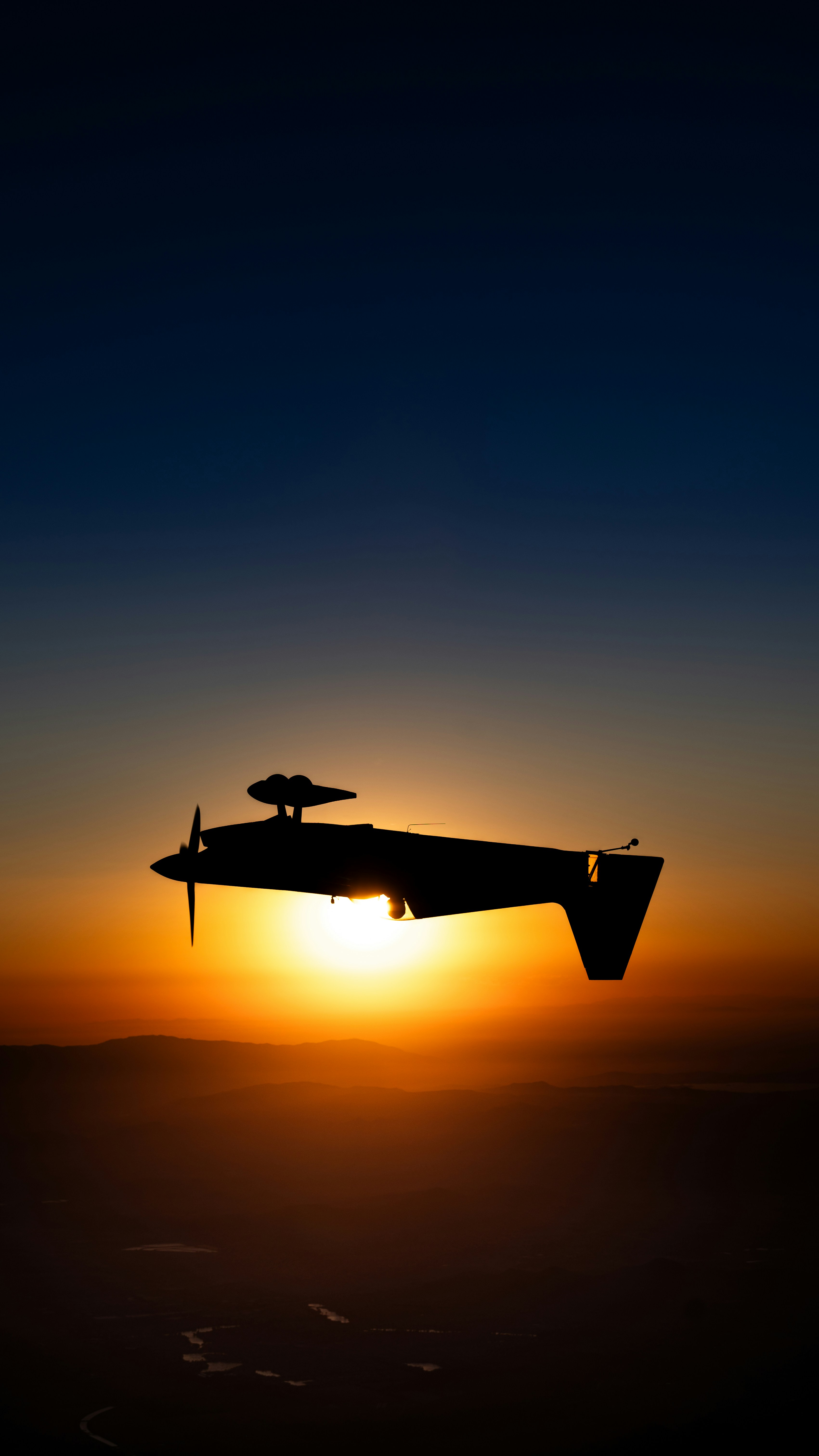 A plane flying in the air at sunset
