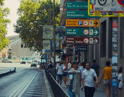 A group of people walking down a street next to tall buildings