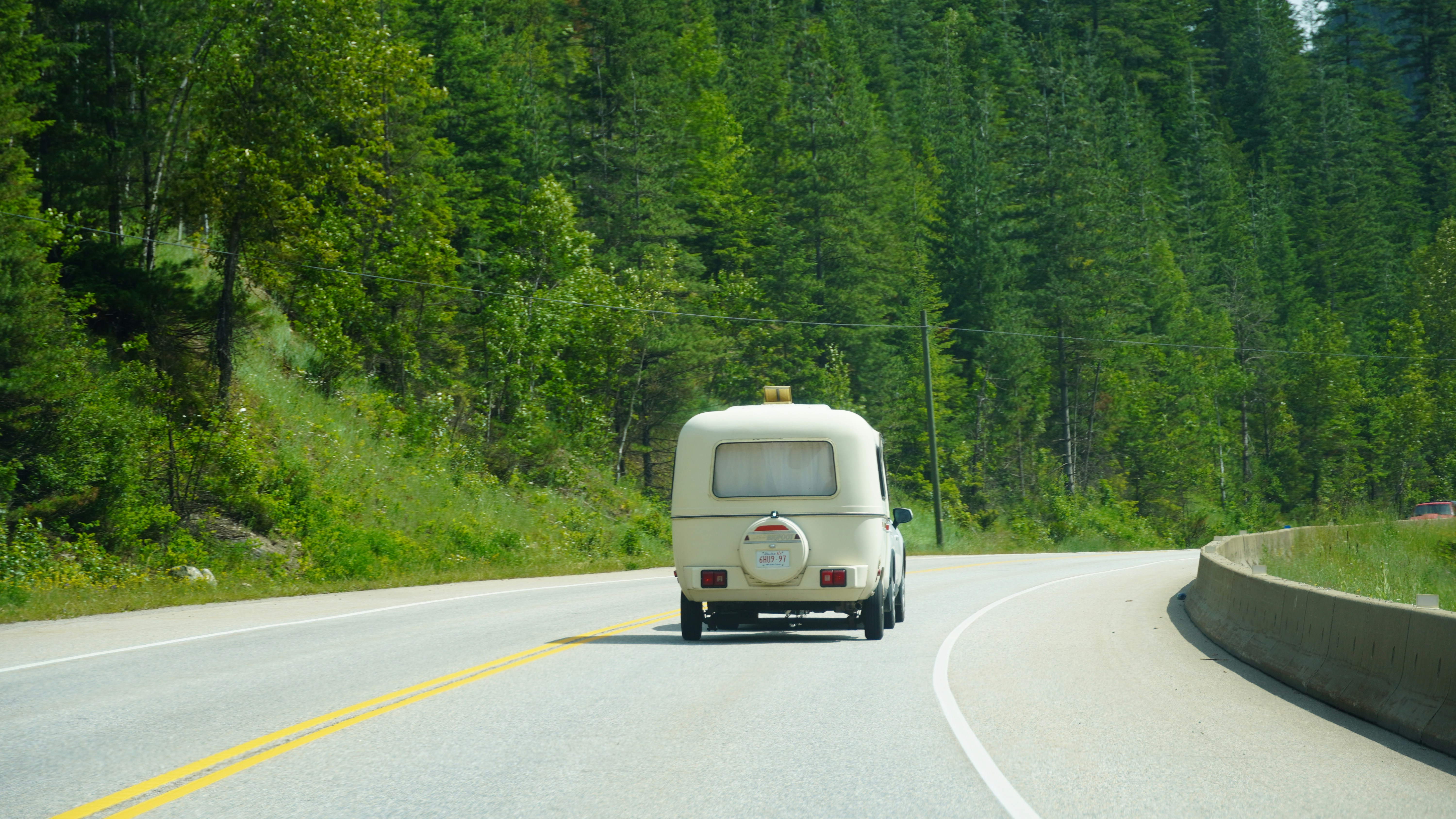 A van driving down a road next to a forest