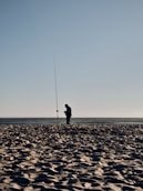 A man standing on top of a sandy beach next to the ocean