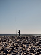 A man standing on top of a sandy beach next to the ocean