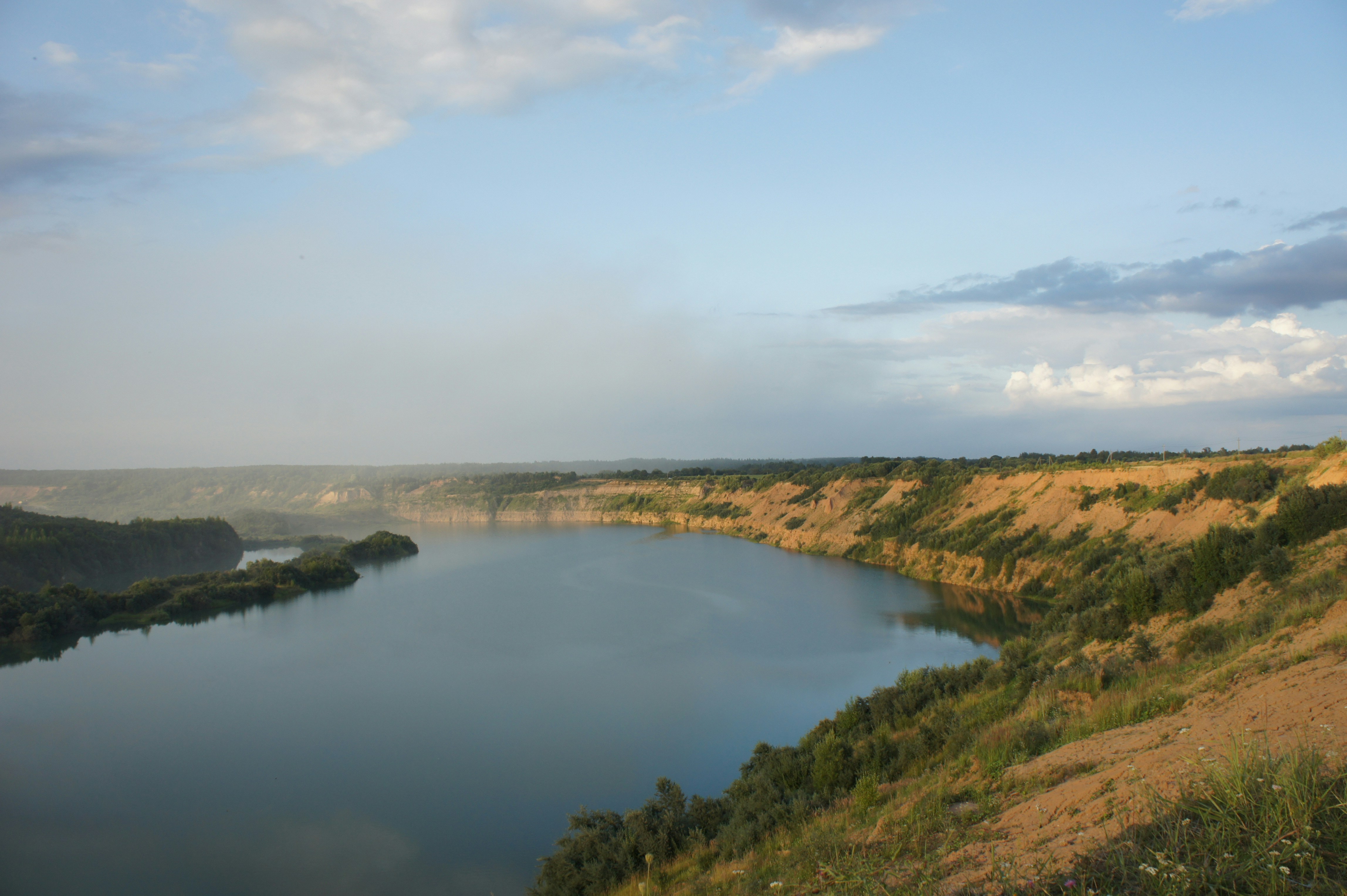 A large body of water surrounded by a lush green hillside