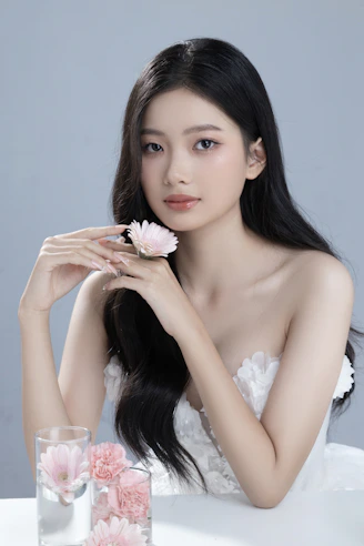 A woman sitting at a table with a flower in her hand