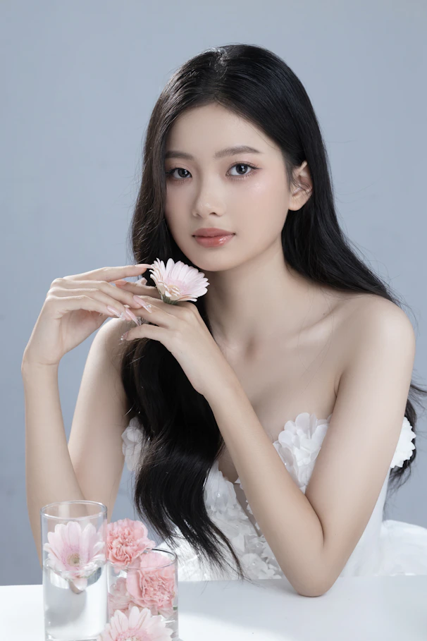 A woman sitting at a table with a flower in her hand