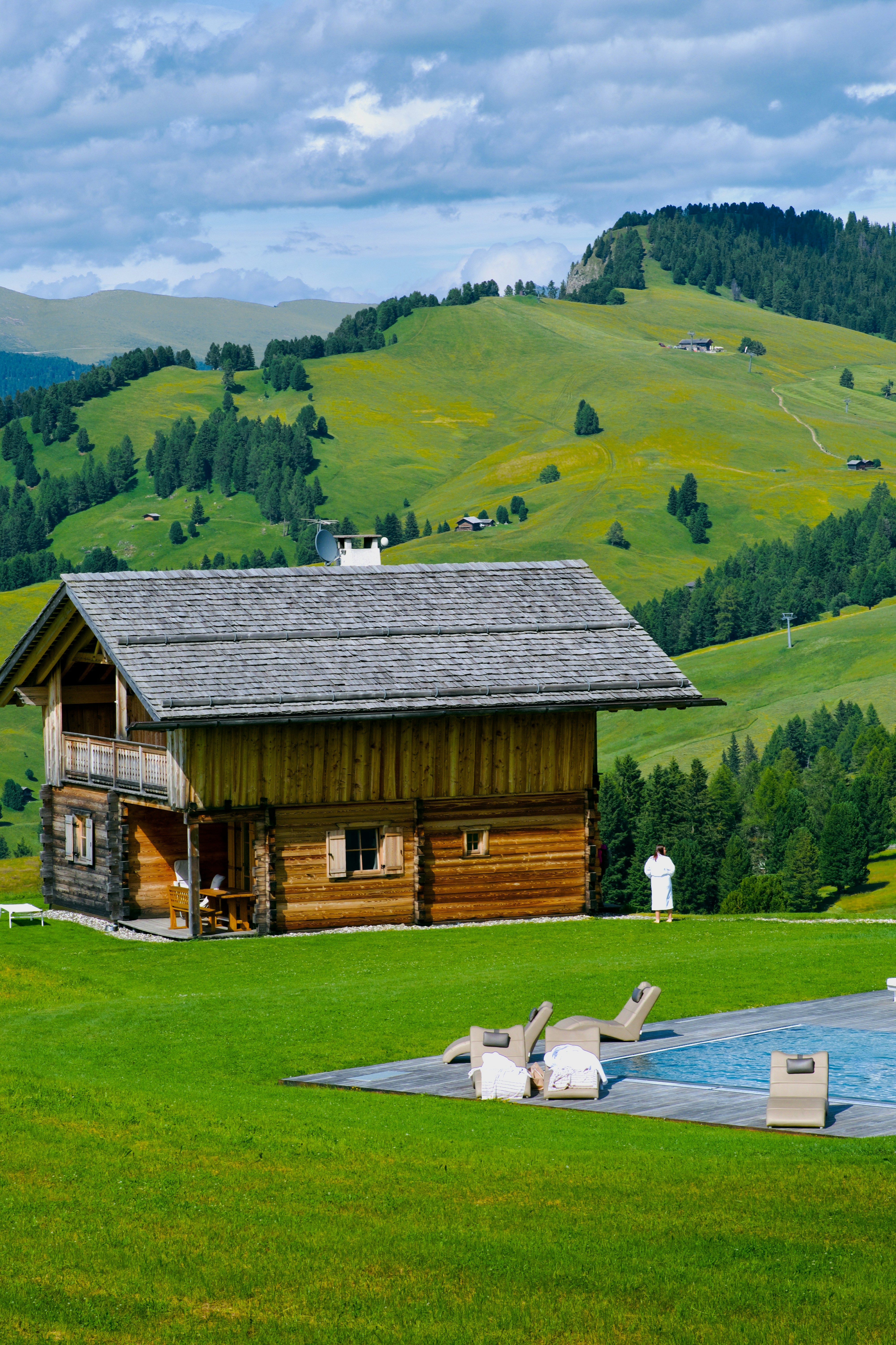 A wooden cabin sitting on top of a lush green hillside